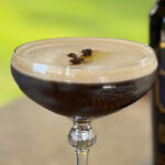 Close-up of an Espresso Martini garnished with a slice of ginger and three coffee beans